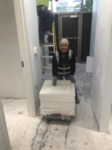 worker smiling and moving pieces of flooring